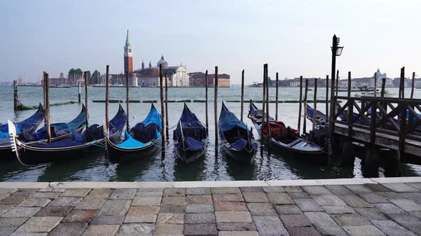 Long Line of Big Navy Gondolas Moored To Thin Wooden Pillars