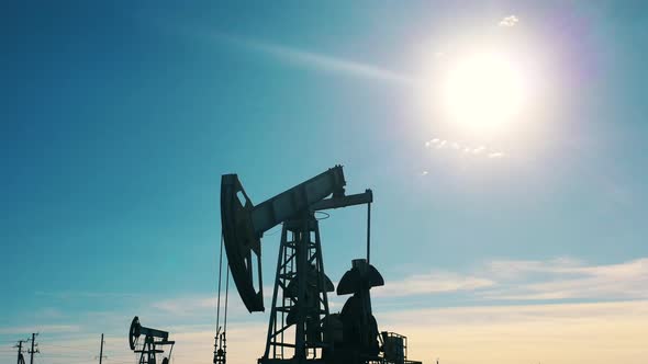 Silhouette of a Working Oil Pumpjack in an Oil Field