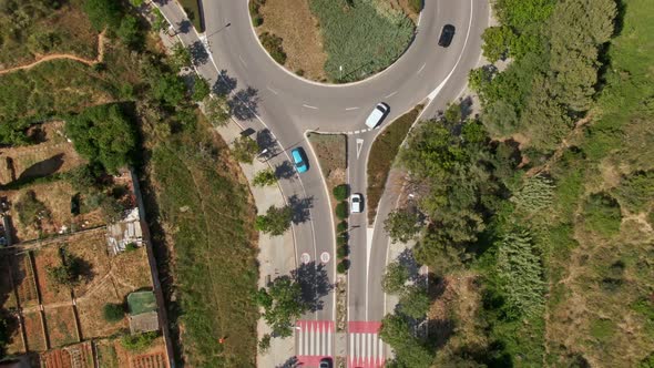 Vehicles driving around roundabout in rural Spain landscape, aerial top down view