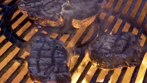 Closeup of two large pieces of filet mignon on the grill with flames licking at them and nice grill