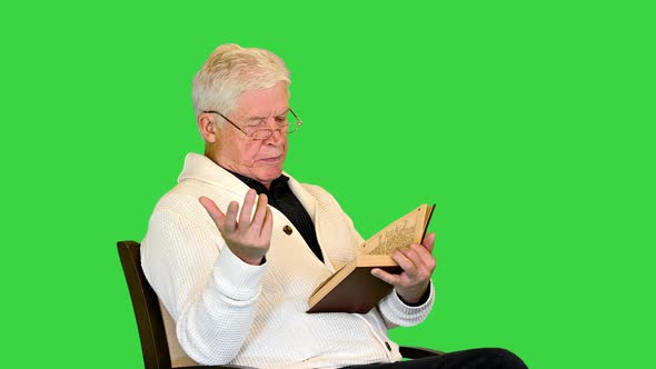 Senior Man Reading Aloud a Book on Camera on a Green Screen Chroma Key