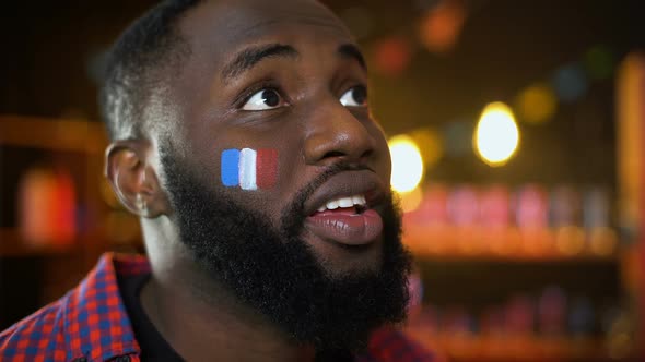 Very Emotional Black Fan With French Flag Painted on Cheek Cheering for Team