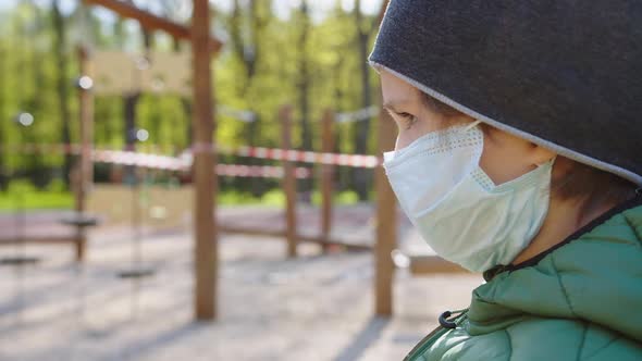 a Boy Wearing a Protective Mask Near a Closed Playground