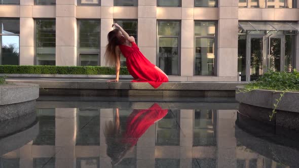 Beautiful Young Girl Dancing on the Street of a Modern City and Is Reflected in the Water. She Is