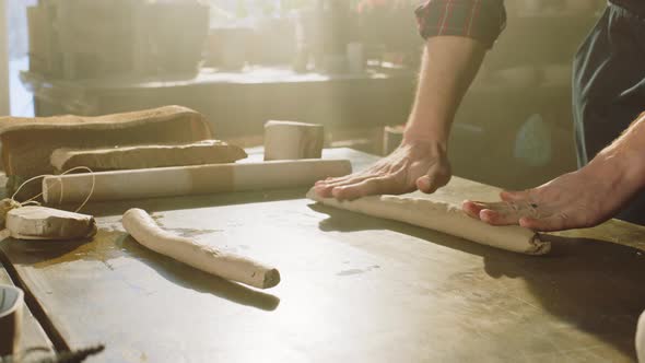 Piece of Raw Clay Is Being Rolled Out By Man