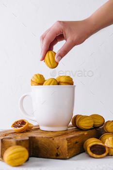 Hand placing a cookie on a cup filled with cookies