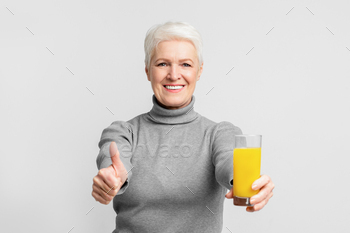 Happy senior promoting healthy drink with thumbs-up