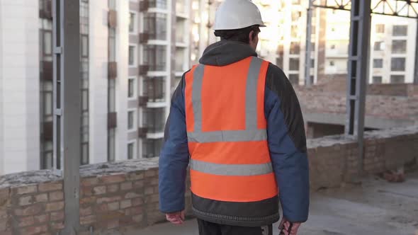 The foreman walks through the construction site.