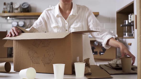 The Girl Collects And Folds Cardboard Paper Garbage For Recycling In A Special Box With The Sign