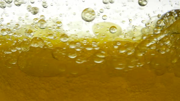 Bubbles of Golden Fluid. The Olive Oil Is Stirred in a Circle in a Bowl and Air Bubbles Appear. The