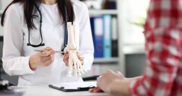 A Woman Orthopedist Shows a Model of a Human Foot