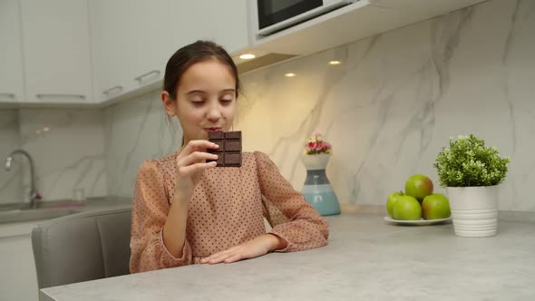 Happy Preteen Girl Eating Chocolate at Domestic Kitchen