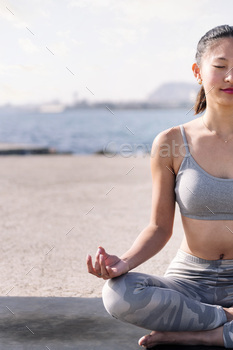 woman doing yoga meditation sitting by the sea