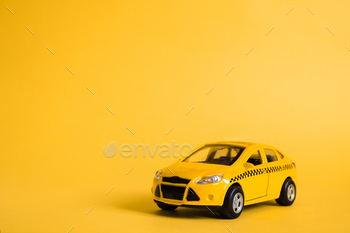 Urban taxi and delivery service concept. Toy yellow taxi car model. Copy space for text, banner