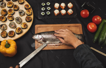 man using a knife to cut the backbone of the fish