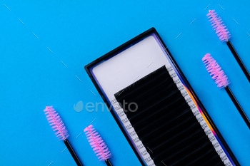 Eyelash extensions and brushes on blue background
