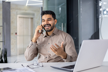 Smiling businessman talking on phone at modern office desk