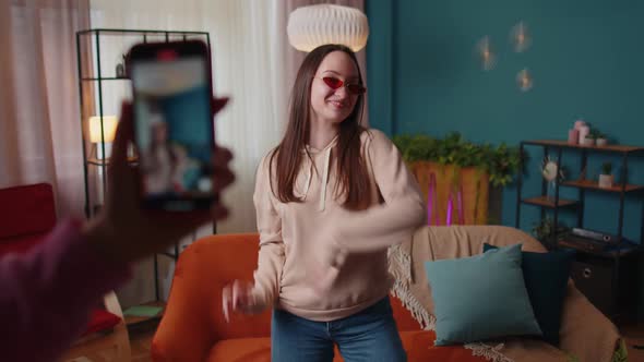 Joyful Blogger Teen Girl Dancing at Camera Filming Video Using Mobile Phone at Home in Living Room