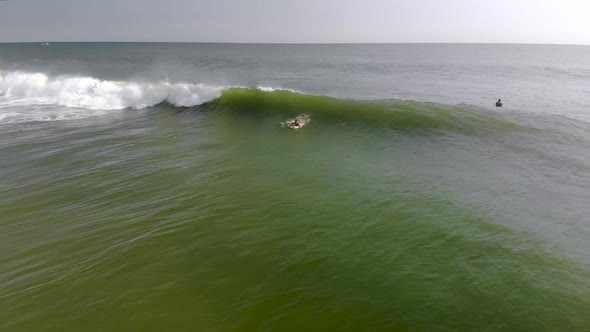 Epic drone tracking shot of surfer riding a wave.