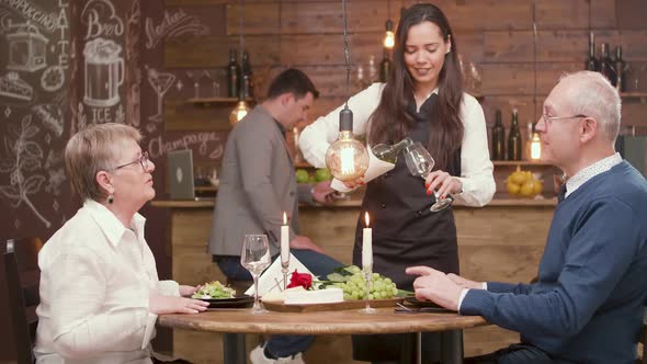 Waitress Pouring Wine To a Old Couple on a Date