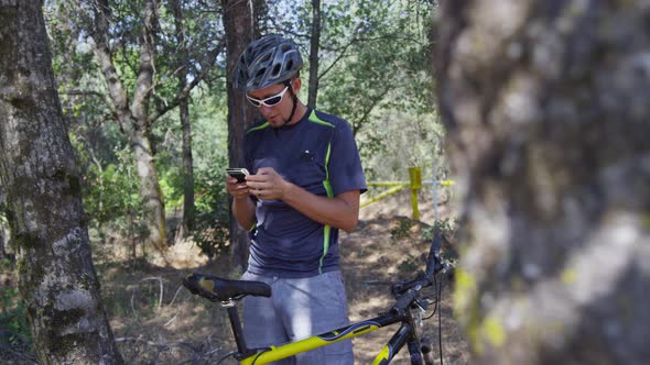 Mountain biker takes a break to check cell phone