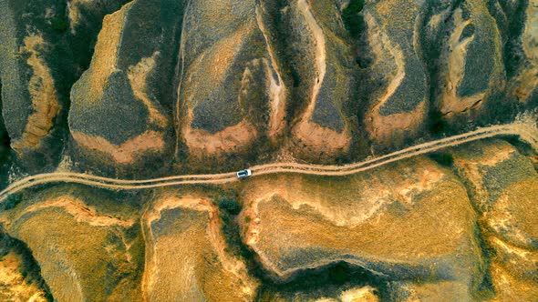 Aerial View on Top Cars Traveling in the Canyon on a Dirt Road Between Large Sand Mountains