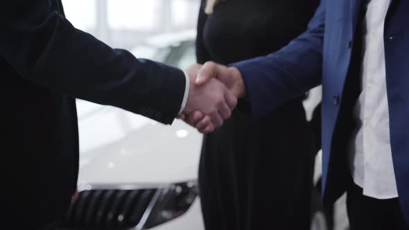 Handshake of Unrecognizable Men in Car Dealership. Caucasian Trader Shaking Hand of Middle Eastern
