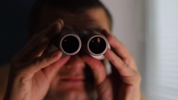 Man Spying on People Using Binoculars for Observation