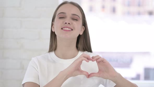 Portrait of Attractive Young Woman Making Heart Shape