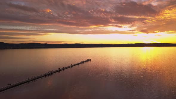 Amazing sunset at the Long Jetty Wharf Pier in Sydney, Australia. Aerial zoom in above silhouettes o