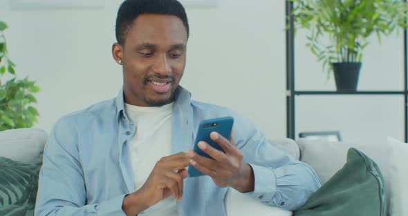 Young African American Man Holding Smartphone Watching Social Media Stories Video Using Mobile App