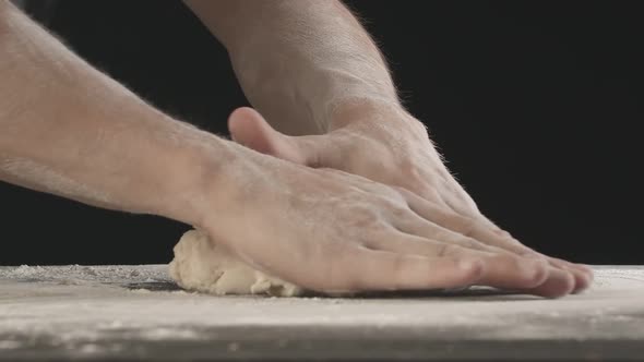 Male Hands Divide Baking Dough Into Shares on a Board Sprinkled with Flour