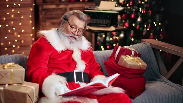 Santa Claus in Festive Costume Natural Beard Reading Children Wish List Book