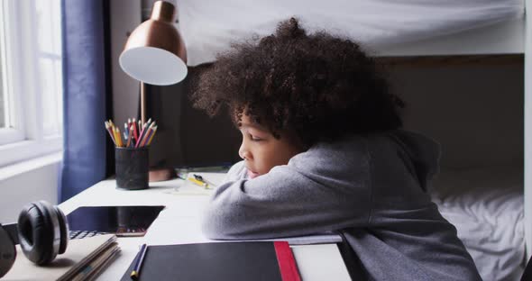 Mixed race girl sitting by desk looking through window