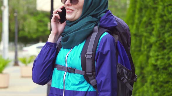 Girl Tourist in a Headscarf and Sunglasses in a Backpack Talking on the Phone Slow Mo