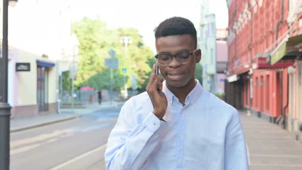 African Man Talking on Phone While Walking on the Street