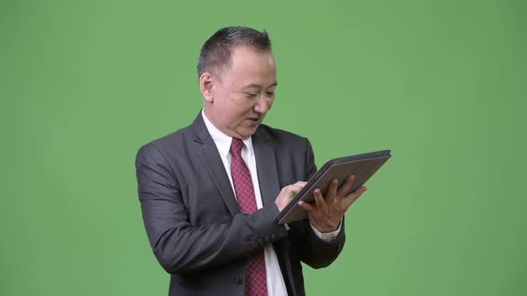 Mature Japanese Businessman Working with Digital Tablet