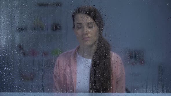 Husband Putting Hands on Wife's Shoulder Behind Rainy Window Family Support