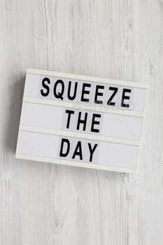 'Squeeze the day' on a lightbox on a white wooden background