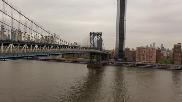 An aerial view over the East River on a cloudy day. The drone camera dolly in along the north side o