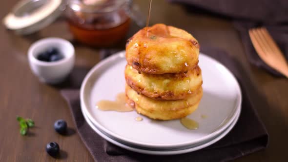 Pouring Syrniki with maple syrup