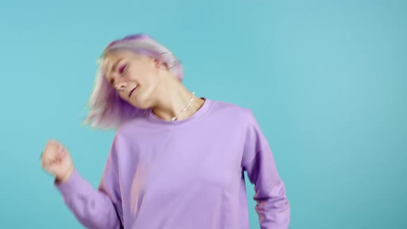 Beautiful Hipster Woman Dancing with Colorful Hairstyle Energetically and Actively on Blue Studio