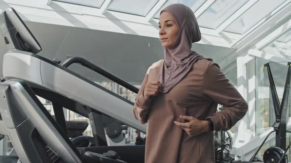 Muslim Woman Running on Treadmill while Training in Gym