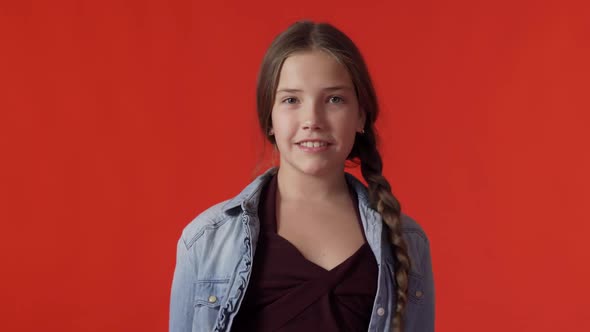 A Young Teenage Caucasian Girl with a Long Braid Smiles As She Looks Into the Camera