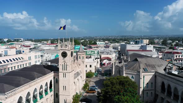 Drone moves over the roofs from Barbados Parliament building with barbadian flag in Bridgetown