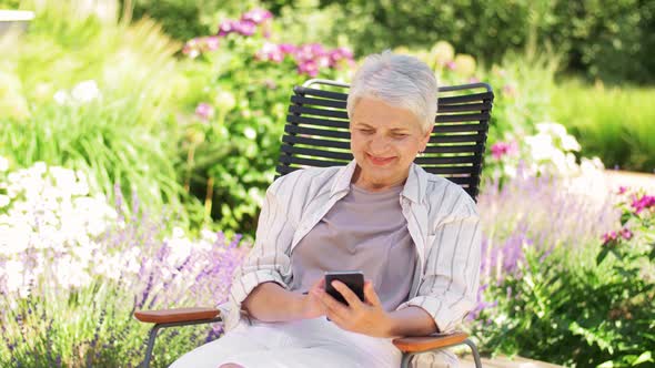 Happy Senior Woman with Phone at Summer Garden