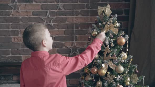 Blond Kid Rearranges Bow Decorations on Christmas Tree
