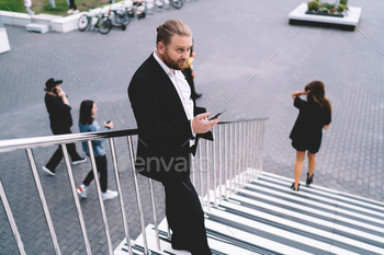 Pondering businessman with smartphone chatting