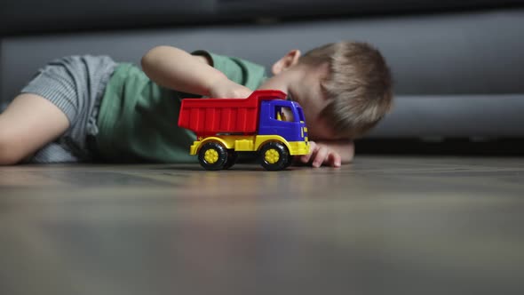 Caucasian Preschooler Boy Kid Child Playing Toy Car Truck on Floor Livingroom