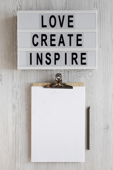 'Love create inspire' words on a lightbox, clipboard with blank sheet of paper